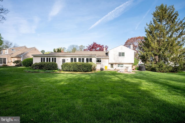 back of house featuring a chimney, a yard, and a patio