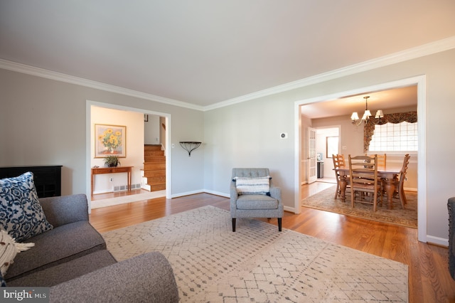 living room with crown molding, visible vents, baseboards, an inviting chandelier, and wood finished floors