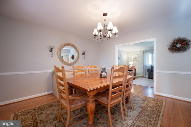 dining area featuring wood finished floors, a chandelier, and baseboards
