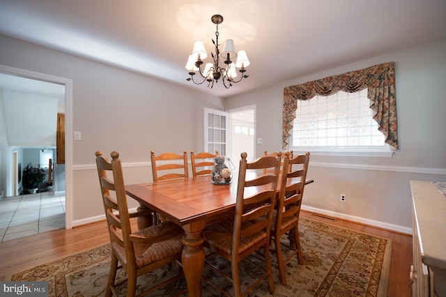dining space featuring light wood finished floors, visible vents, a chandelier, and baseboards