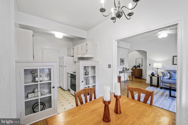 dining area featuring an inviting chandelier, arched walkways, and light wood finished floors