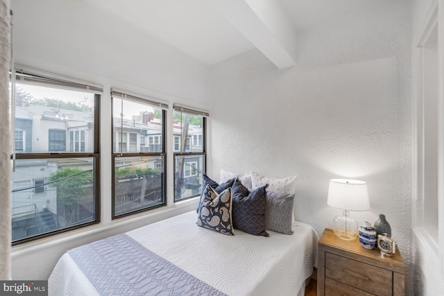 bedroom with a textured wall and beam ceiling