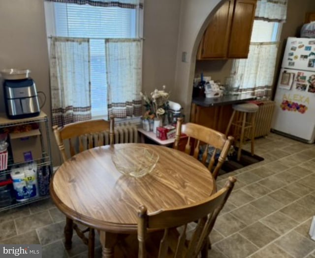 dining space with arched walkways and radiator