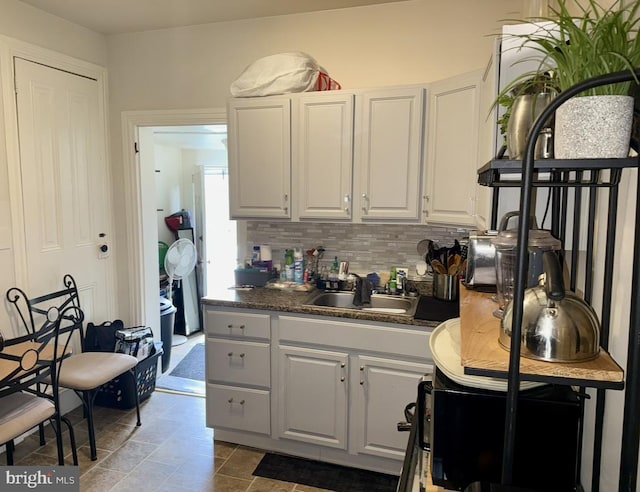 kitchen featuring a sink, dark countertops, decorative backsplash, and white cabinetry