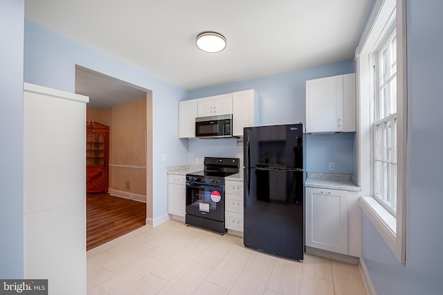 kitchen with white cabinetry, black appliances, a wealth of natural light, and light countertops