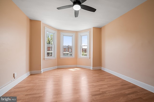 empty room featuring a ceiling fan, light wood-style flooring, and baseboards