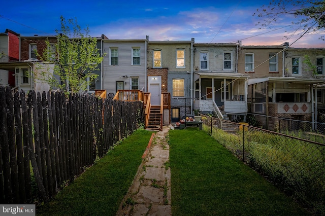 124 Collins Ave, Baltimore, MD 21229 - back of property at dusk featuring stairs, a fenced backyard, a yard, and a deck