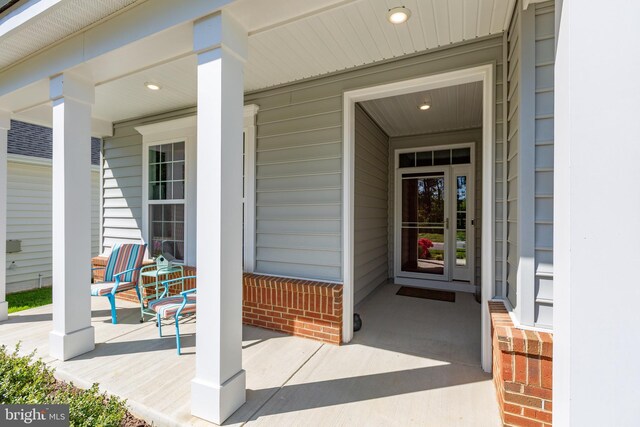 view of exterior entry featuring brick siding and covered porch