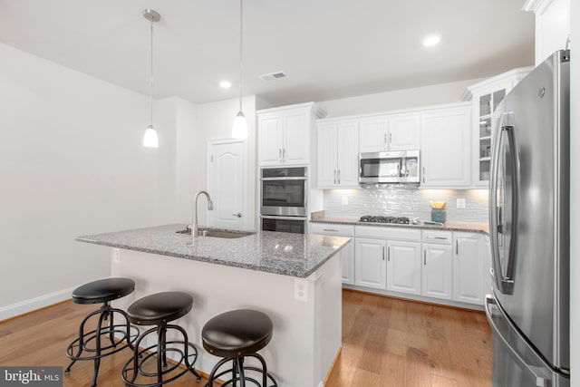 kitchen with a sink, appliances with stainless steel finishes, backsplash, and white cabinets