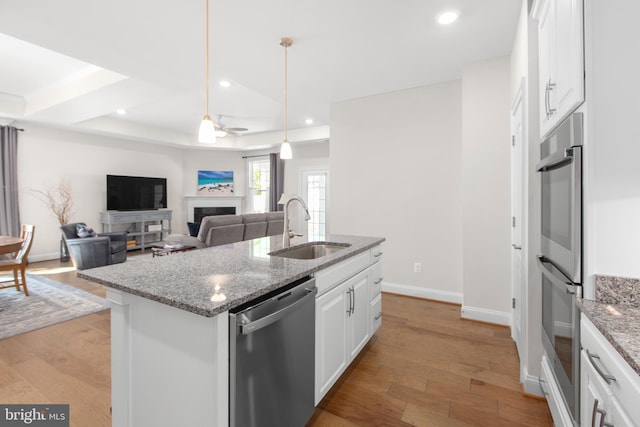 kitchen featuring a sink, a kitchen island with sink, white cabinetry, a ceiling fan, and appliances with stainless steel finishes