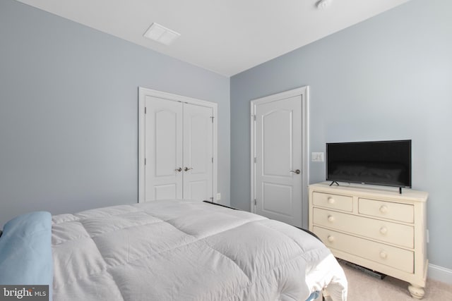 carpeted bedroom featuring baseboards, a closet, and visible vents
