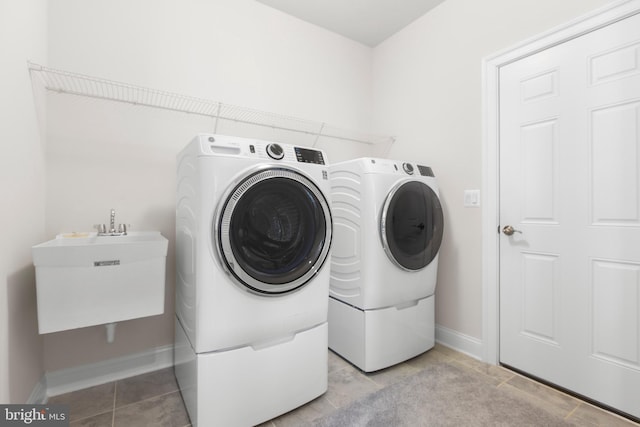 laundry area with laundry area, baseboards, light tile patterned floors, and washer and dryer