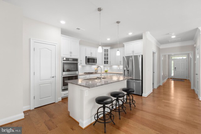 kitchen featuring decorative backsplash, light wood-style flooring, white cabinets, and stainless steel appliances