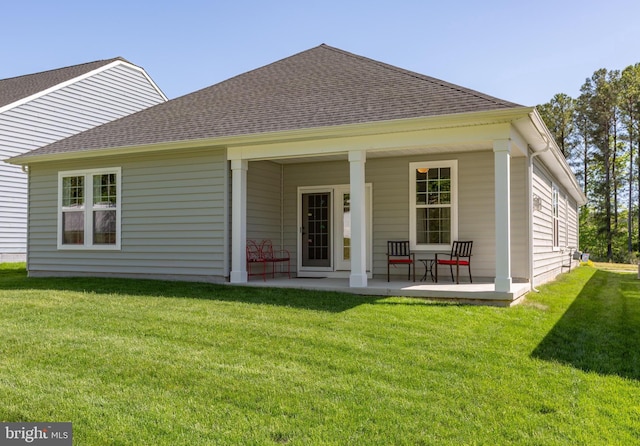 back of property with a lawn, covered porch, and a shingled roof