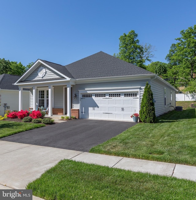 ranch-style home featuring covered porch, driveway, a front yard, and a garage