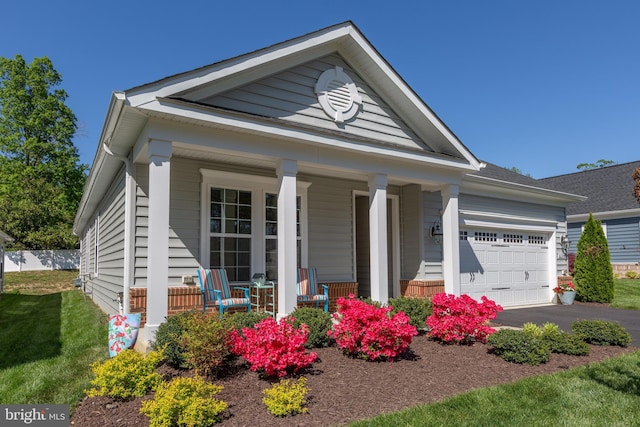 view of front of home with a porch, aphalt driveway, a front lawn, and a garage