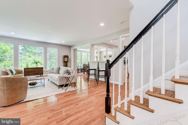 living area featuring stairs, light wood-type flooring, and recessed lighting