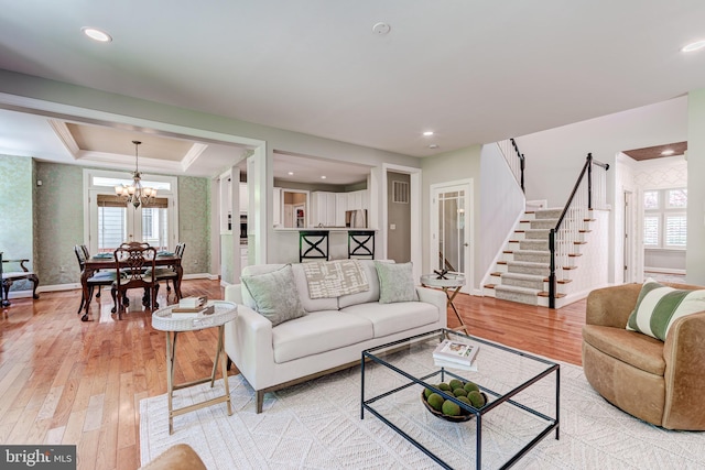 living room with healthy amount of natural light, stairs, light wood-type flooring, a chandelier, and recessed lighting