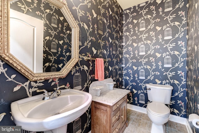 half bathroom with toilet, a sink, baseboards, and tile patterned floors