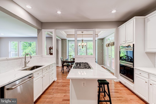 kitchen featuring appliances with stainless steel finishes, a sink, a kitchen island, backsplash, and recessed lighting
