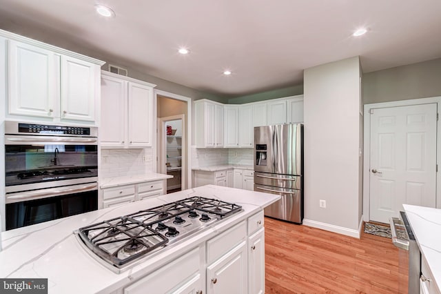 kitchen with stainless steel appliances, white cabinetry, tasteful backsplash, recessed lighting, and light wood-style floors