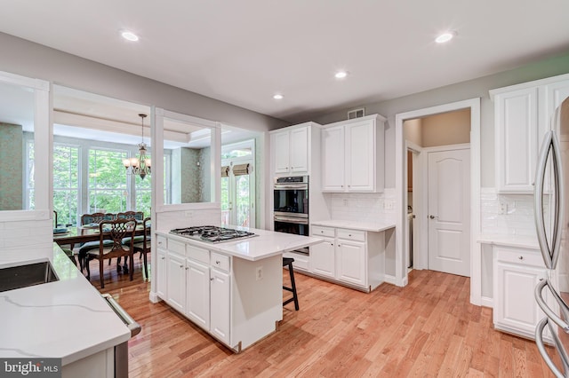 kitchen featuring appliances with stainless steel finishes, tasteful backsplash, white cabinetry, and recessed lighting