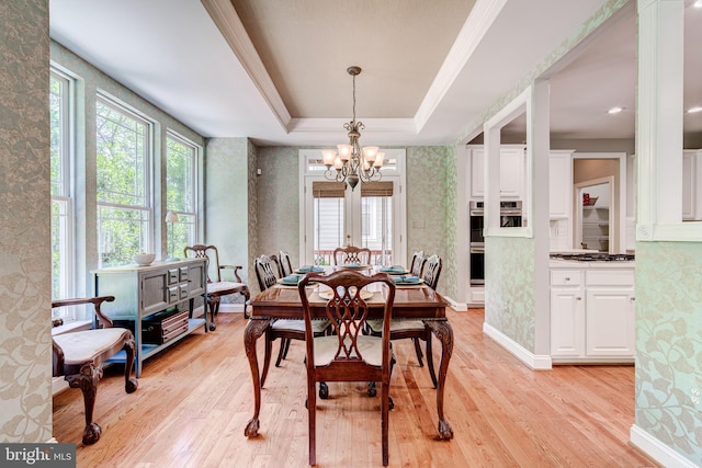 dining space featuring a chandelier, light wood-style flooring, a raised ceiling, wallpapered walls, and baseboards
