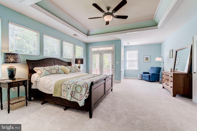 bedroom featuring a tray ceiling, light colored carpet, access to exterior, ornamental molding, and a ceiling fan