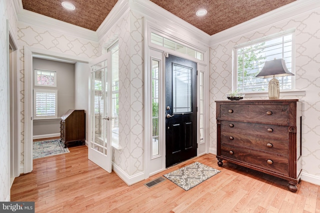 entrance foyer featuring crown molding, wallpapered walls, light wood-type flooring, baseboards, and healthy amount of natural light