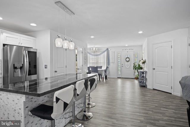 kitchen with stainless steel refrigerator with ice dispenser, a notable chandelier, wood finished floors, and recessed lighting