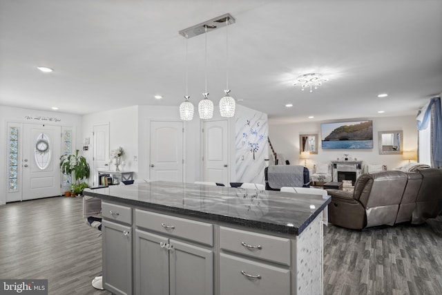 kitchen with dark wood-type flooring, recessed lighting, dark stone counters, and gray cabinetry