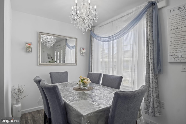 dining area with baseboards, an inviting chandelier, and wood finished floors