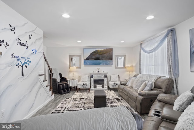 living room featuring recessed lighting, a fireplace, wood finished floors, and stairway