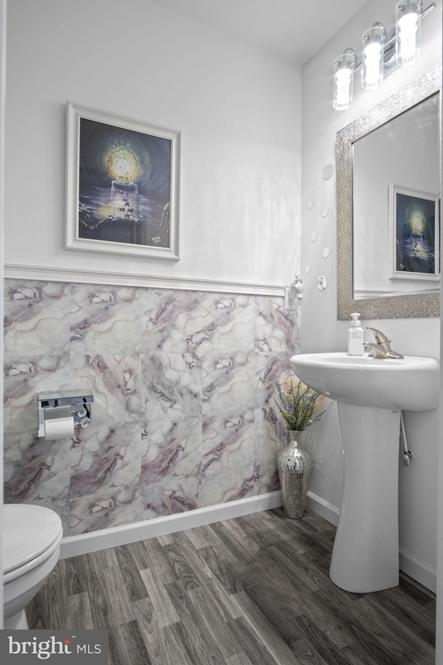 half bathroom featuring baseboards, toilet, and wood finished floors