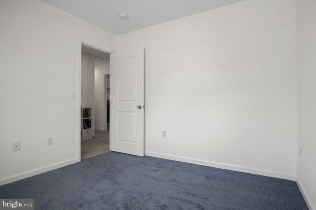 unfurnished room with carpet flooring and baseboards