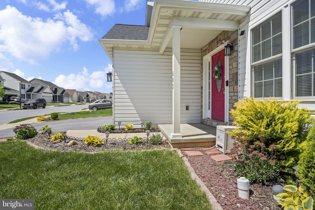 doorway to property featuring roof with shingles, ac unit, and a residential view