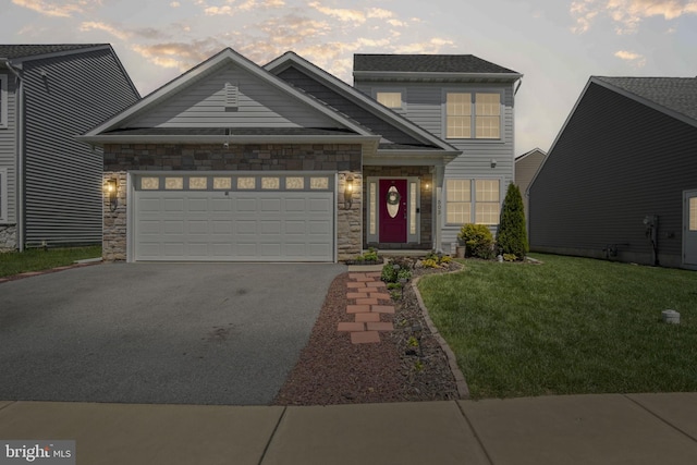 view of front of property with a yard, an attached garage, stone siding, and aphalt driveway