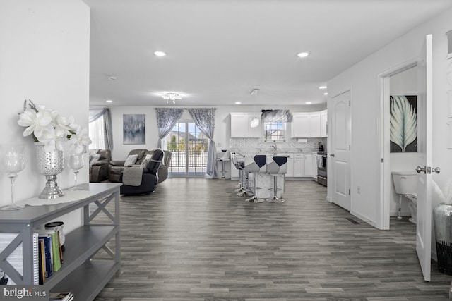 living area featuring dark wood-style flooring, recessed lighting, and visible vents