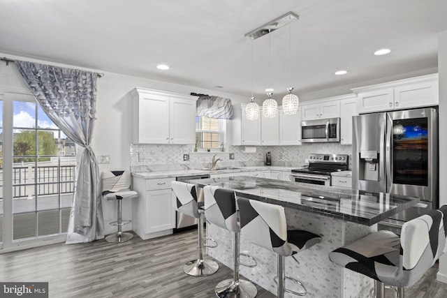 kitchen with a sink, appliances with stainless steel finishes, wood finished floors, and a kitchen bar