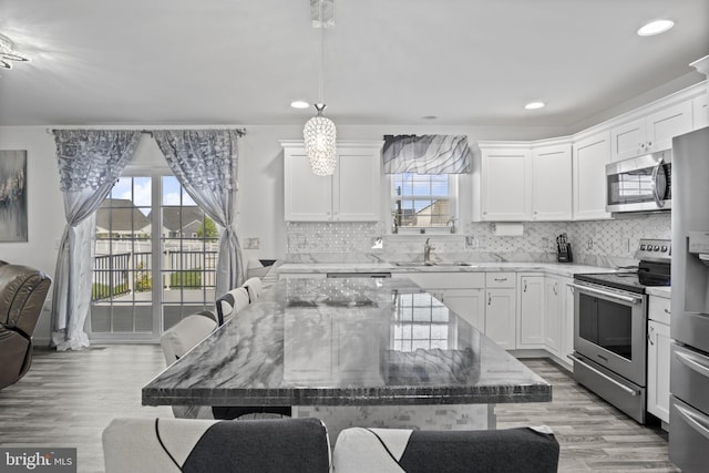 kitchen with decorative backsplash, light stone countertops, a breakfast bar, a sink, and stainless steel appliances