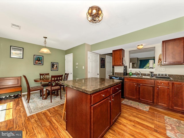 kitchen featuring a kitchen island, light wood-type flooring, a sink, visible vents, and dishwashing machine