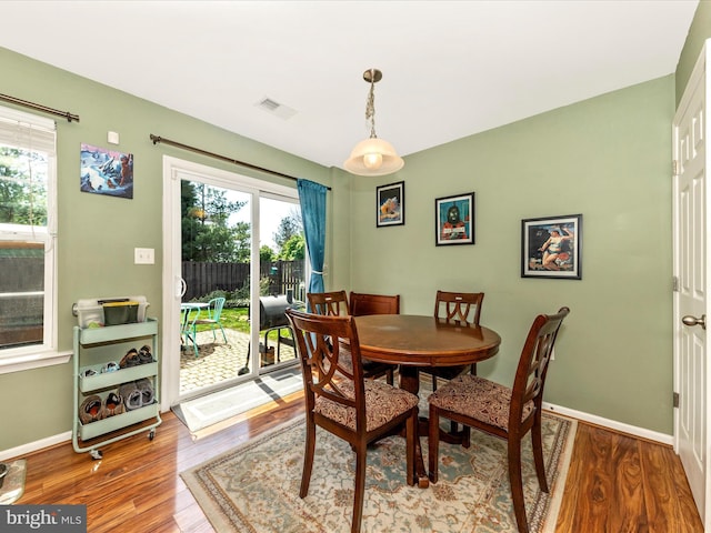 dining area with wood finished floors, visible vents, and baseboards