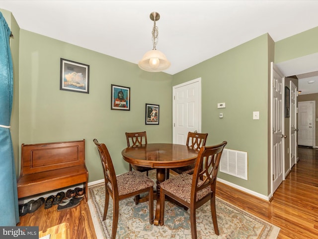 dining area with baseboards, visible vents, and wood finished floors