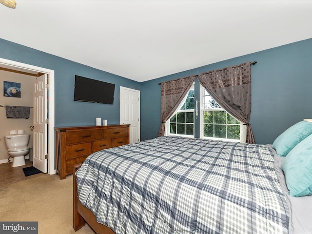 bedroom with baseboards, light carpet, and ensuite bath