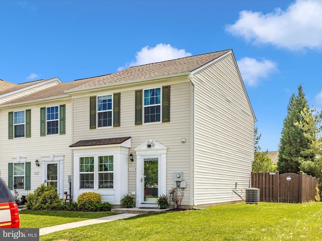 view of front of property with a front lawn, fence, a shingled roof, and central AC unit