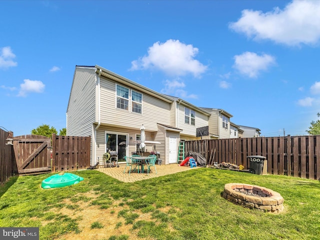 back of property with a fire pit, a gate, and a fenced backyard