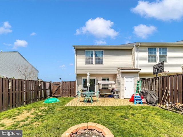 back of property with a patio, a yard, a fenced backyard, a gate, and a fire pit