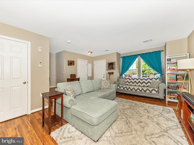 living area featuring visible vents and wood finished floors