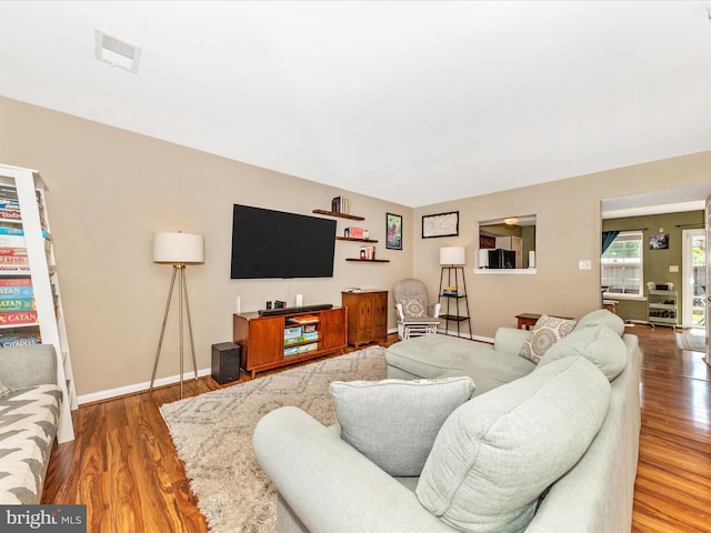 living room featuring visible vents, wood finished floors, and baseboards