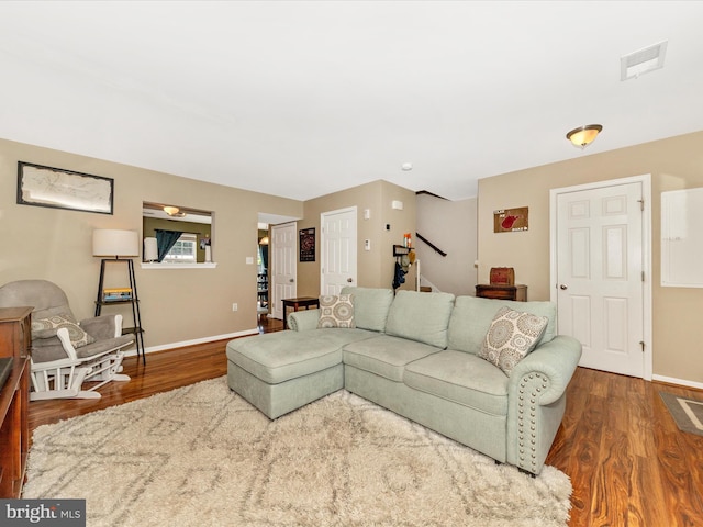 living area featuring baseboards, visible vents, wood finished floors, and stairway